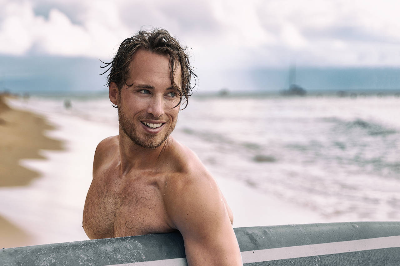 Sexy surfer surfing man with surfboard. Handsome young male athl